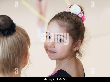 Little cute ballerina in studio looking on camera. Sport, training, fitness, stretching, dancing, yoga, active lifestyle concept Stock Photo