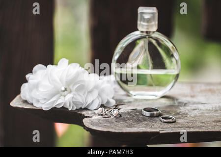 Bride's wedding set perfume, earrings, necklace, jewels rings and lace garter on wooden table Stock Photo