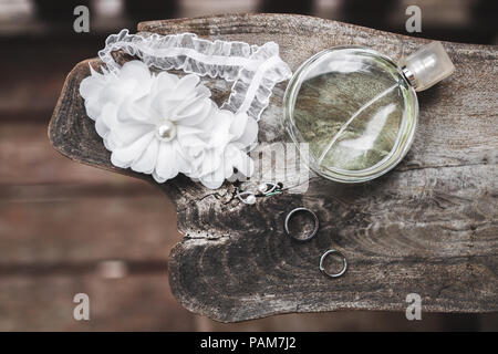 Bride's wedding set perfume, earrings, necklace, jewels rings and lace garter on wooden table Stock Photo