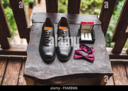 Man wedding set, leather shoes, rings in box and bow tie on wooden texture Stock Photo