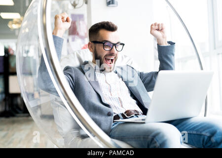 Portrait of handsome bearded man working sitting in transparent plastic chair Stock Photo