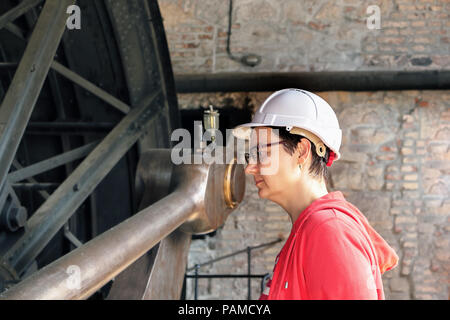 Young female engineer, mechanist checking antique machinery. Stock Photo