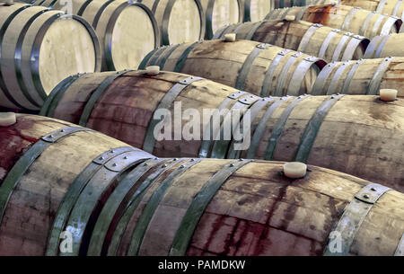 Old and stained wooden wine barrels in rows inside a wine cellar Stock Photo