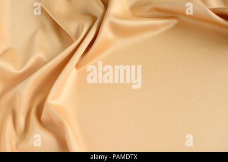 Close up of ripples in gold colored silk fabric. Satin textile background. Free copy space. Stock Photo