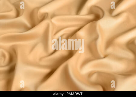 Close up of ripples in gold colored silk fabric. Satin textile background. Stock Photo