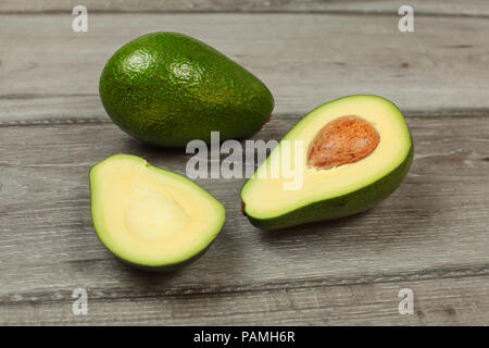 Avocado cut in half with whole pear in back, on gray wood table. Stock Photo