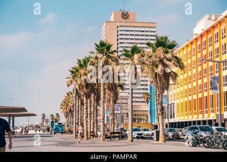 the brightly coloured Dan Hotel in Tel Aviv on a hot summers day. Palm trees line the street in front of it Stock Photo