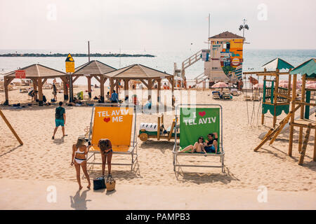 beachgoers relax in chairs and on the sand at the colourful Frishman Beach in Tel Aviv, Israel Stock Photo