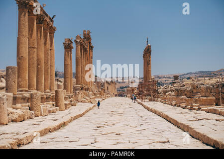 old ancient Greco-Roman columns line cobblestone streets on a warm summers day in Jerash, Jordan Stock Photo