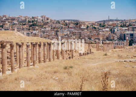 old ancient Greco-Roman columns line cobblestone streets on a warm summers day in Jerash, Jordan Stock Photo