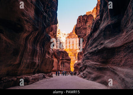 a tour group walks down the main path into Petra, Jordan. The canyon was carved by the rock splitting during an earthquake