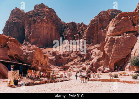 shops selling souvenirs line the main path in from Petra, Jordan, while some locals with mules carry goods out Stock Photo