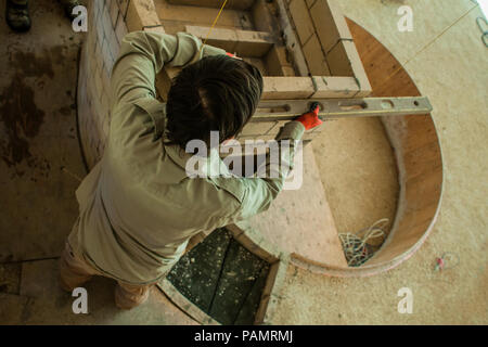 Brickmason using a spirit level to build a brick wall, seen from above Stock Photo