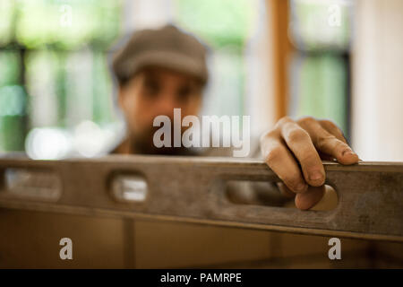 Blurred man holding a spirit level with hand in focus Stock Photo