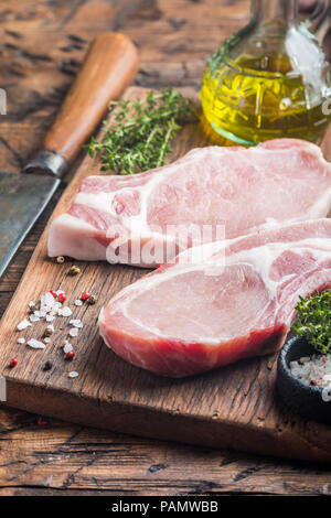 Raw pork meat chopes with herbs, oil and spices on wooden background. Stock Photo