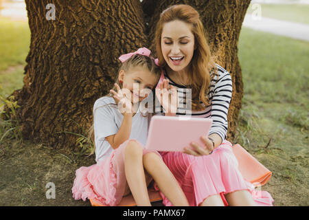 Beaming mother and daughter having video chat with father Stock Photo