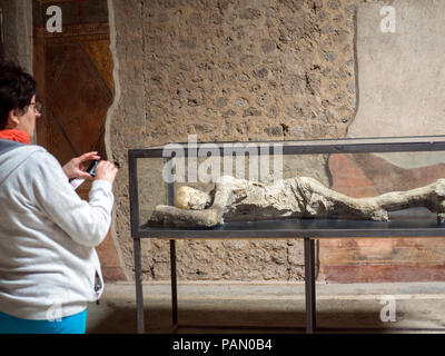 A tourist look at petrified human bodies inside the Villa of Mysteries in Pompeii, Italy. Stock Photo