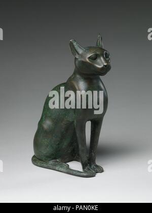 Cat Statuette intended to contain a mummified cat. Dimensions: h. (including tangs) 32 cm (12 5/8 in); w. 11.9 (4 11/16 in); d. 23.3 cm (9 3/16 in)  h. (cat alone) 27.4 cm (10 13/16 in). Date: 332-30 B.C..  The cat was the sacred animal of the goddess Bastet, a great and benevolent Egyptian goddess. In her honor, mummified cats, sometimes in impressive bronze or wooden containers, were donated at her temples, of which the most important were located at Bubastis and Saqqara. The mummies were then buried within her temple precincts.   This statue was the container for a mummified cat. Clearly th Stock Photo