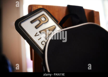 A licence plate peaks out of a school backpack resting on a chair Stock Photo