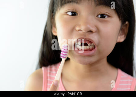 Little Asian girl without front teeth holding a tooth brush Stock Photo