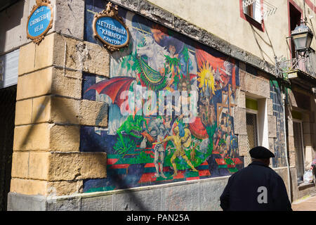 Basque Spain, rear view of a senior man wearing a beret walking past a colorful illustrated wall in the Old Town area of Bilbao, Northern Spain. Stock Photo