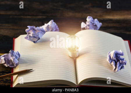 Concept idea. Growing light bulb on vintage book with crumpled papers and pencil. Copy space for your text. conceptual great ideas are always availabl Stock Photo