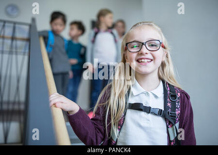 Portrait of happy schoolgirl with classmates on staircase leaving school Stock Photo