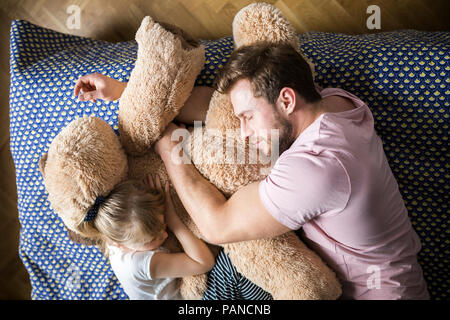 Father and daughter taking a nap, cuddling with teddy bear Stock Photo