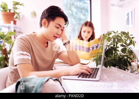 Dark-haired student feeling bored while studying during break Stock Photo
