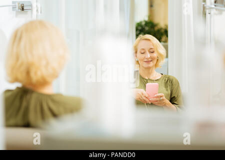 Cheerful nice woman using her gadget Stock Photo