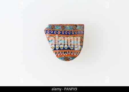 Semi-eliptical inlay, pattern formed by fused bars of diamonds, circles, dentelations. Dimensions: H. 1.8 × W. 2 cm (11/16 × 13/16 in.). Date: 100 BC-100 AD.  A mosaic glass technique allowed multiples of an image to be created: a figural or design composition was made by bundling colored glass canes, which were then drawn out into a long bar . The bar was then sectioned at right angles, probably by striking the bar with appropriate tools, to produce small inlay tiles. The tile would then be smoothed and polished on the face intended to appear outwards. Museum: Metropolitan Museum of Art, New  Stock Photo