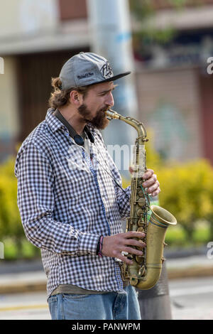 Young man playing a saxaphone on the stree for money at Cuenca Ecuador Stock Photo