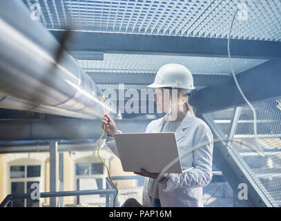 Female technician working on pipeworks, using laptop Stock Photo