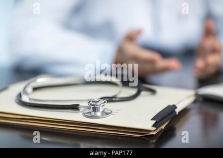 Files and stethoscope on desk in medical practice with doctor in background Stock Photo