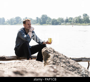 Mature man sitting at Rhine riverbank, looking at distance Stock Photo