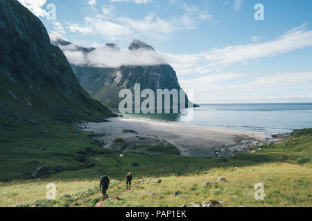 Norway, Lofoten, Moskenesoy, Young men hiking at Kvalvika Beach Stock Photo
