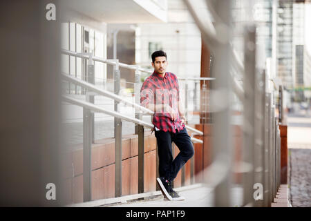 Young man leaning on railing Stock Photo