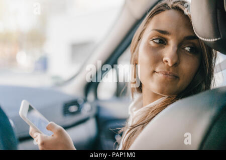 Young businesswoman sitting in car, using smartphone Stock Photo