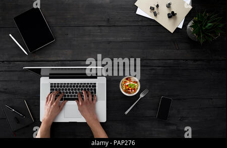 Person with laptop and snack sitting at desk Stock Photo