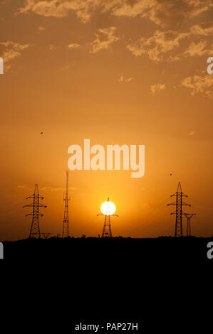 High Voltage Power Poles at Sunset. Looks Like They Are Being Charged From the Sun. Stock Photo