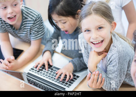 Happy pupils using laptop in class Stock Photo