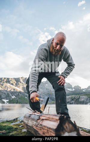 Norway, Lofoten, Moskenesoy, Young man chopping wood Stock Photo