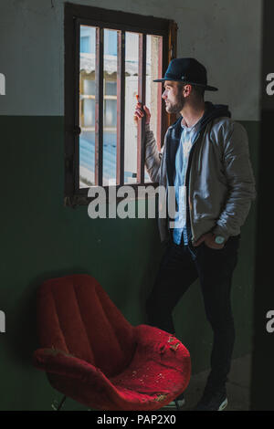 Bearded man wearing black hat, looking out of window Stock Photo