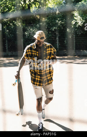 Cool young man in skate park, using smartphone Stock Photo