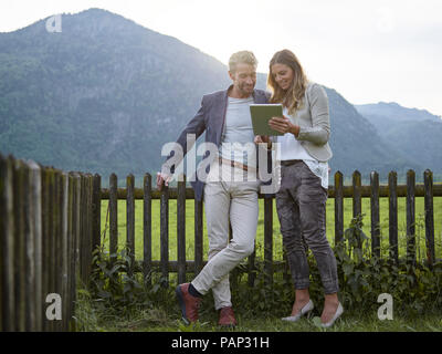 Man and woman sharing tablet in rural landscape Stock Photo