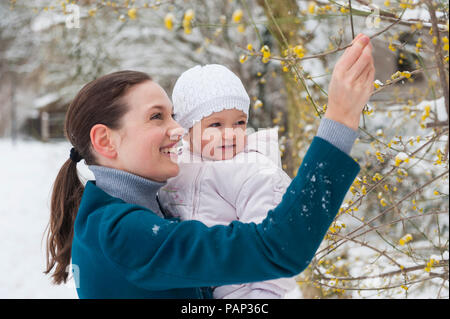 Portrait of happy mother with baby girl in snow-covered landscape Stock Photo