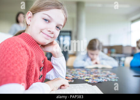 Portrait of smiling schoolgirl with book in school break room Stock Photo