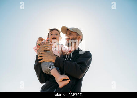 Laughing father holding baby girl at backlight Stock Photo