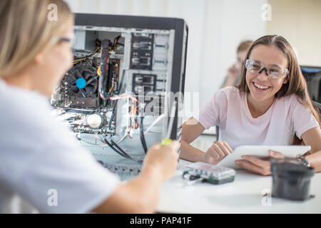 Happy teenage girls assembling computer in class Stock Photo