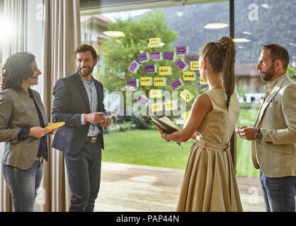 Colleagues discussing with sticky notes at the window Stock Photo